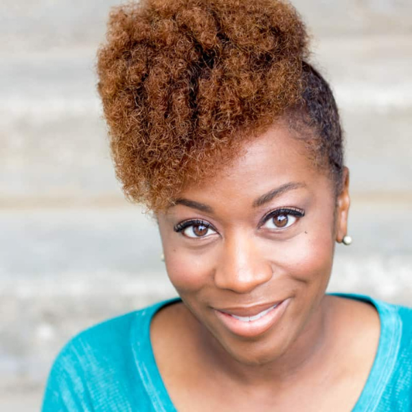 Actress Alexis J Roston in a light blue shirt in front of a gray blackground