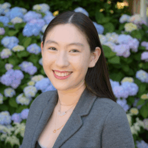 Abigail Kanes in a gray blazer in front of a flowery background