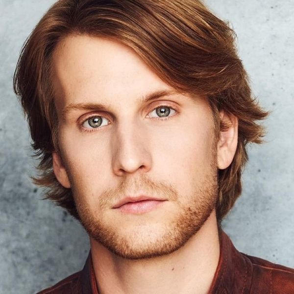 Actor Gavin Rhys Morgan in a red flannel shirt posed in front of a gray backdrop
