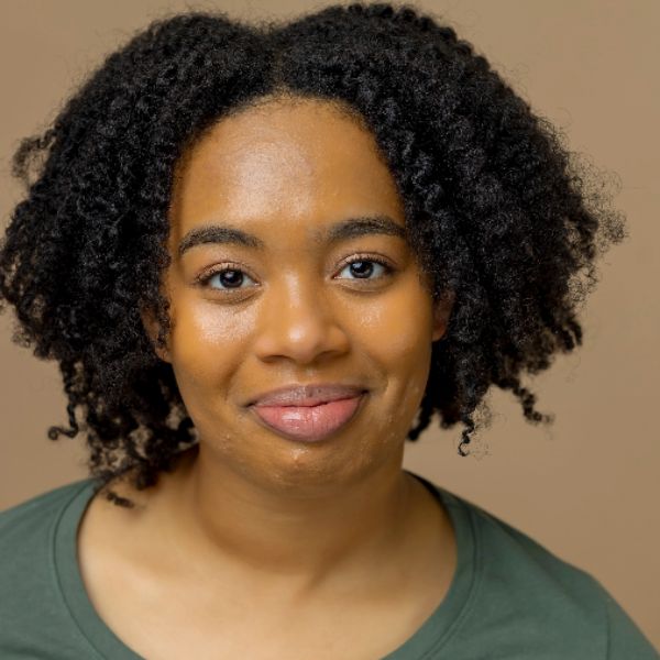 Actor Elexis Selmon in a green shirt, posed in front of a light brown backdrop