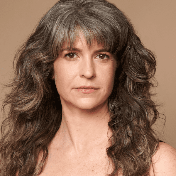 Actress Lucy Carapetyan looking at the camera, posed in front of a solid brown backdrop