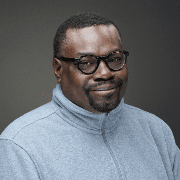 Lee Peters in a blue zip up sweater in front of a gray backdrop