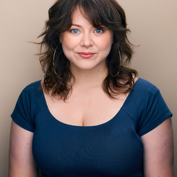 Kelsey McGarth, posed in front of a light brown backdrop. She wears a blue shirt.