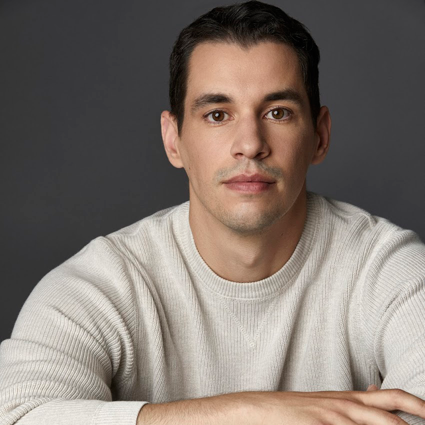 Actor Ryan Hallahan in a white sweater in front of a gray backdrop