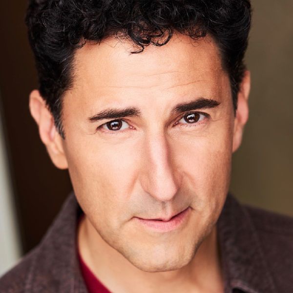 Actor Sean Fprtimatp, a man with brown hair in a brown jacket and red shirt, shown from the neck up