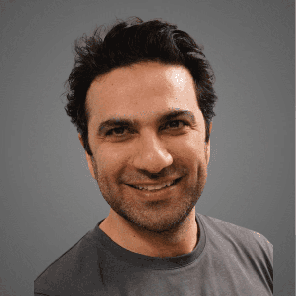 Hamid in a gray shirt posed in front of a gray gradient backdrop
