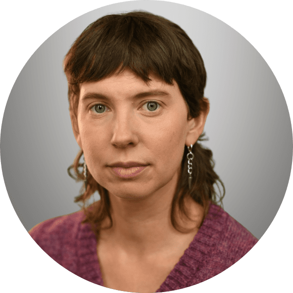 Dinah in a red shirt posed in front of a gray gradient backdrop