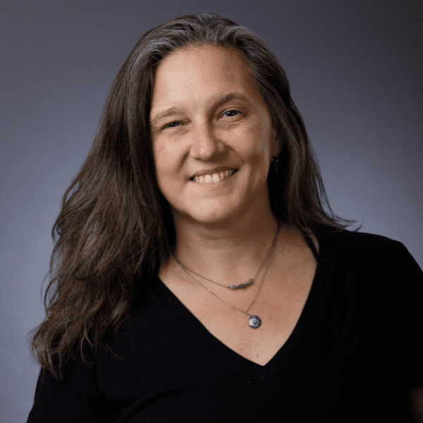 Janet in a black shirt posed in front of a gray backdrop