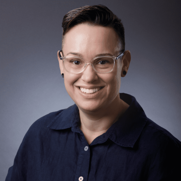 Georgette in a blue shirt in front of a gray backdrop.